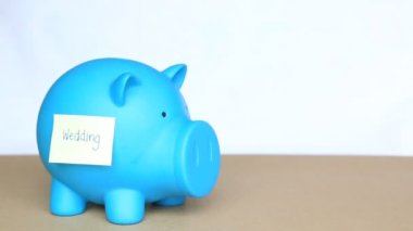 Yapışkan notu ve düğün için para tasarrufu kavramı üzerinde düğün kelime ile mavi piggy banka içinde jeton atın