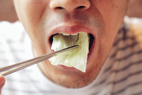 Closeup Asya erkek taze sebze gıda yeme, Napa lahana, çin tarzında çubuk ile. Sağlıklı kavramı ve fikrini gösterin.