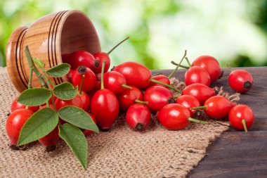 Çuval bezi ve arka plan bulanık ile gemide bir ahşap kase taze kuşburnu çilek