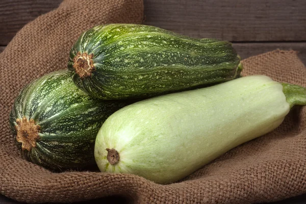 Green zucchini and courgette on sackcloth wooden background — Stock Photo, Image