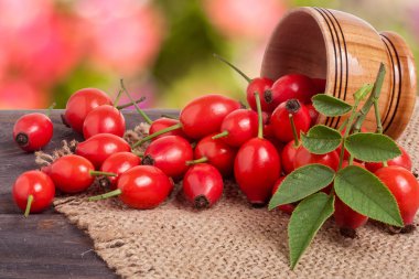 Çuval bezi ve arka plan bulanık ile gemide bir ahşap kase taze kuşburnu çilek