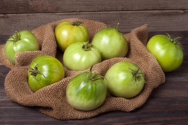 Etwas grüne unreife Tomaten auf dem hölzernen Hintergrund mit Klette — Stockfoto