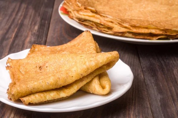 Tunna pannkakor på en vit platta med wood bakgrund — Stockfoto