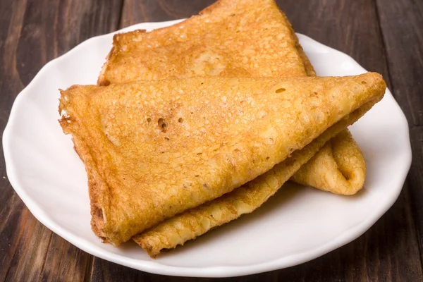 Crêpes fines sur une assiette blanche avec fond en bois — Photo