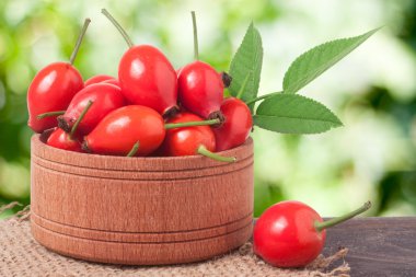 Çuval bezi ve arka plan bulanık ile gemide bir ahşap kase taze kuşburnu çilek