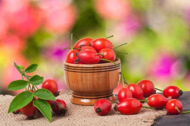 Çuval bezi ve arka plan bulanık ile gemide bir ahşap kase taze kuşburnu çilek