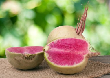 Bahçe arka plan bulanık ile ahşap bir masa üzerinde bir bütün ve dilimli karpuz turp