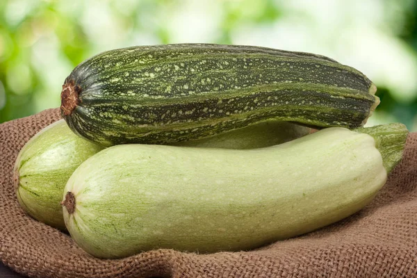 Green zucchini and courgettes on sackcloth with a blurred background — Stock Photo, Image