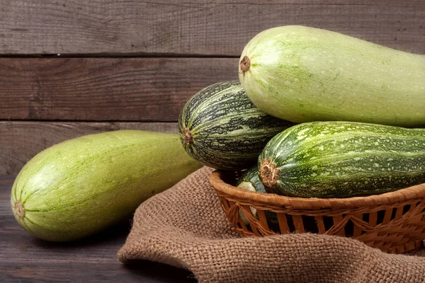 Green zucchini and courgettes on sackcloth wooden background — Stock Photo, Image