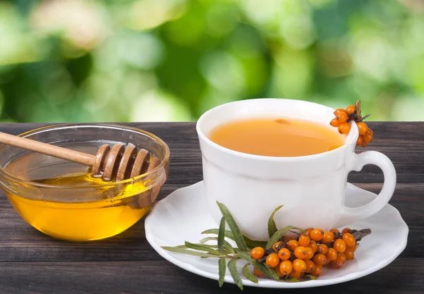 Té de bayas de espino cerval de mar con miel sobre fondo de jardín borroso mesa de madera —  Fotos de Stock