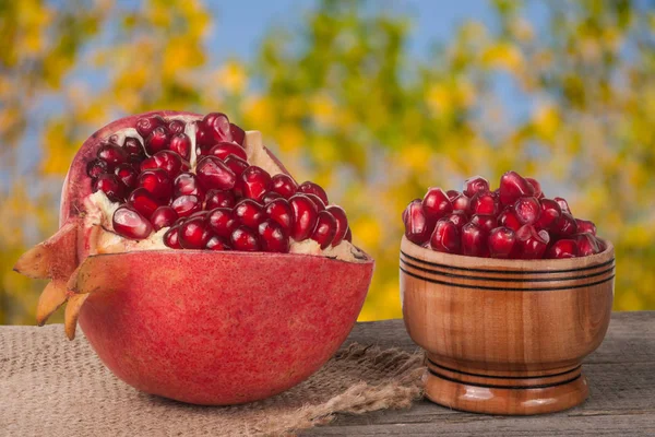 Peeled pomegranate and garnet grains in a bowl on  wooden background — Stock Photo, Image
