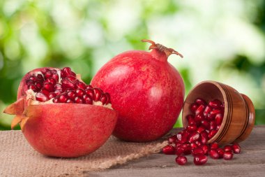 soyulmuş nar ve ahşap arka plan üzerinde bir kasede garnet taneleri