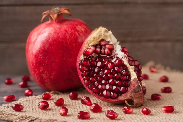 Pomegranate on the old wooden board with sackcloth — Stock Photo, Image