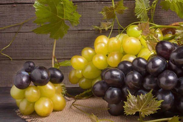 Uvas azules y verdes sobre mesa de madera — Foto de Stock