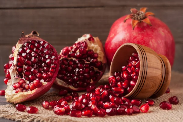 Pomegranate and grains in the bowl on the old wooden board with sackcloth — Stock Photo, Image