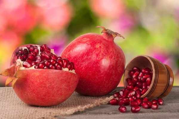 Peeled pomegranate and garnet grains in a bowl on wooden background — Stock Photo, Image