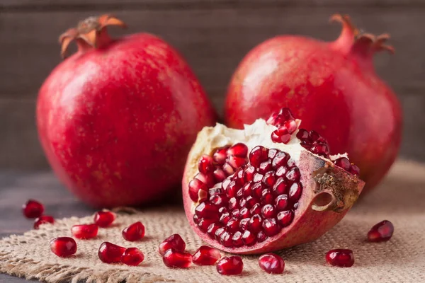 Two pomegranate on the old wooden board with sackcloth — Stock Photo, Image