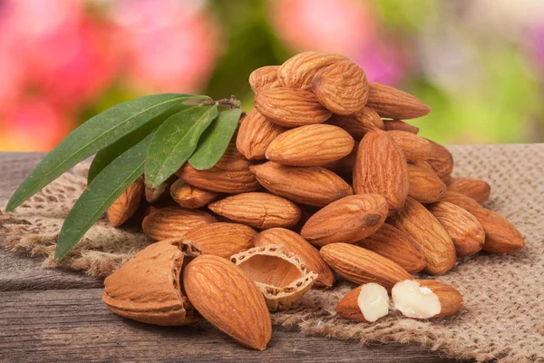 heap of peeled almonds with leaf on a wooden table blurred garden background