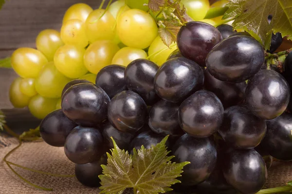 Uvas azules y verdes sobre mesa de madera — Foto de Stock