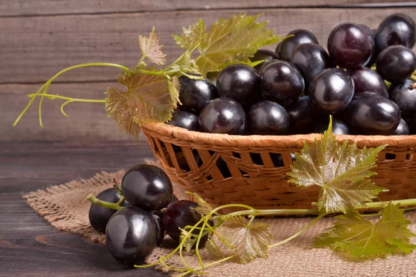 Raisins bleus dans un panier en osier sur une table en bois — Photo