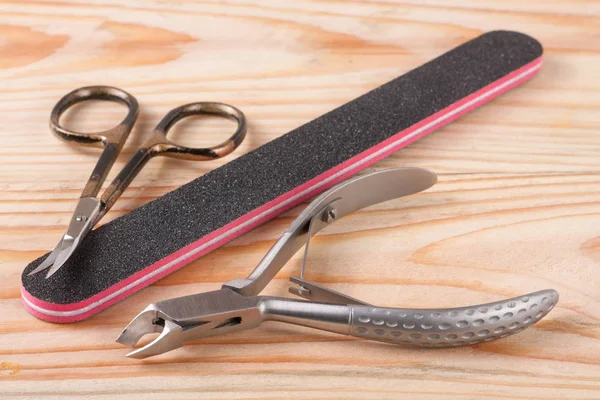 Nail scissors file and clippers to remove the cuticle care products on a light wooden background — Stock Photo, Image