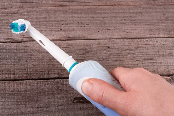 Electric Toothbrush in hand on an old wooden background — Stock Photo, Image