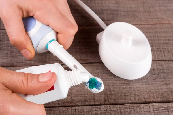 Electric Toothbrush with toothpaste in hand on an old wooden background — Stock Photo, Image