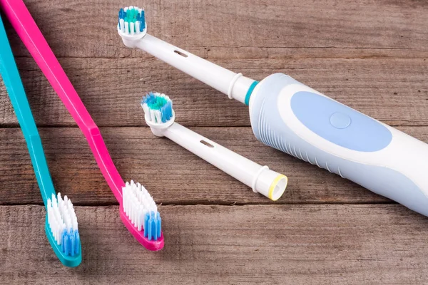 Cepillos de dientes eléctricos y manuales sobre el fondo de madera — Foto de Stock