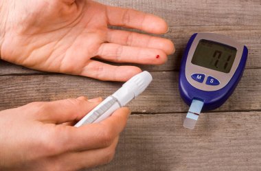 eski bir ahşap zemin üzerinde bir el ile kan şekeri ölçüm cihazı