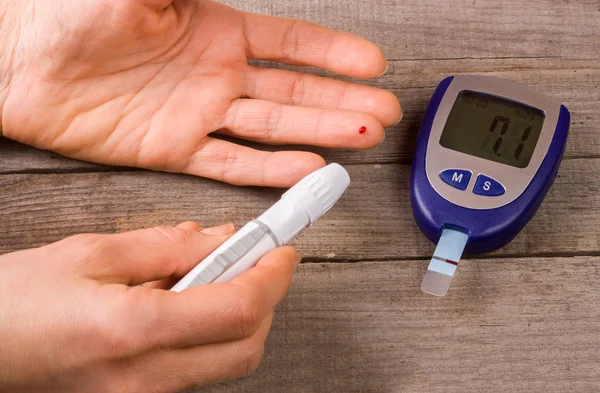 eski bir ahşap zemin üzerinde bir el ile kan şekeri ölçüm cihazı
