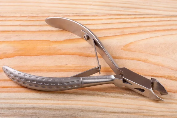 Nail clippers to remove the cuticle and care products on a light wooden background — Stock Photo, Image