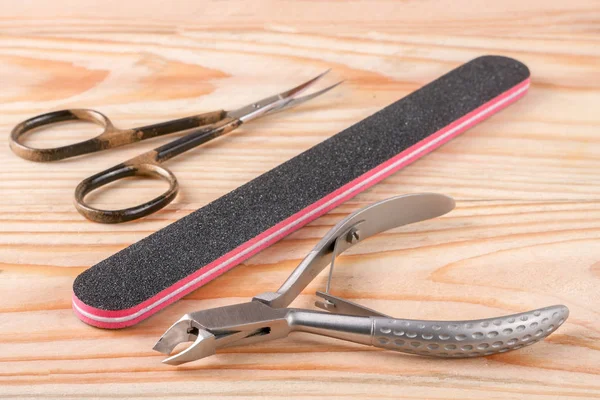 Nagelscheren-Feile und Haarschere zum Entfernen der Nagelhautpflegemittel auf hellem Holzgrund — Stockfoto