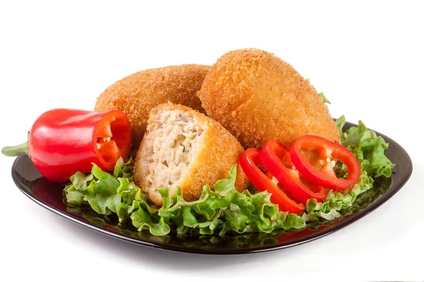 Three fried breaded cutlet with lettuce on a black plate isolated  white background — Stock Photo, Image
