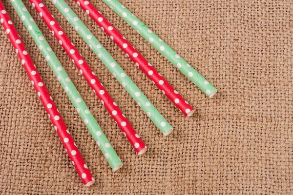 Colorful drinking striped straws on the background of burlap — Stock Photo, Image