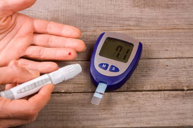 eski bir ahşap zemin üzerinde bir el ile kan şekeri ölçüm cihazı