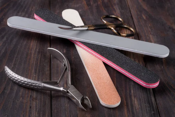 Ножницы для ногтей файл и ножницы для удаления продуктов по уходу за кутикулой на темном деревянном фоне — стоковое фото