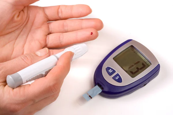 Medidor de glucosa en sangre en la mano sobre fondo azul.