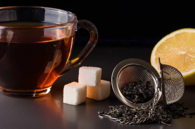 bir süzgeç ve koyu arka plan üzerinde limon ile çay