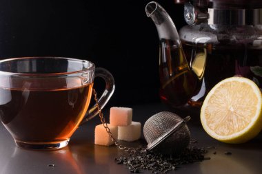 bir süzgeç ve koyu arka plan üzerinde limon ile çay