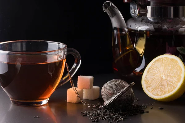bir süzgeç ve koyu arka plan üzerinde limon ile çay