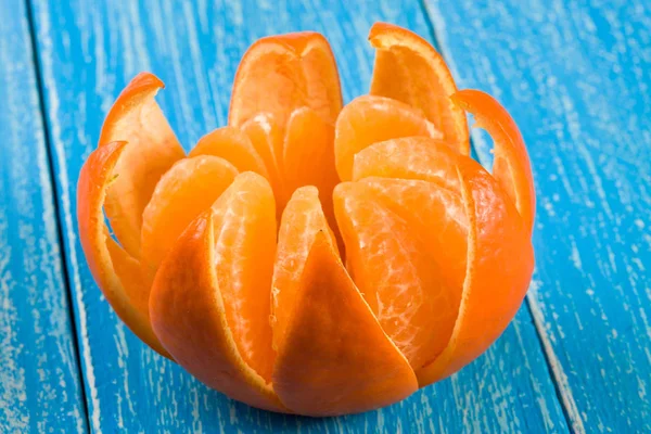 Eine geschälte Mandarine auf blauem Holzgrund — Stockfoto