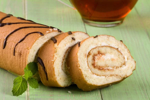 Biscuit swiss roll on a green wooden background — Stock Photo, Image