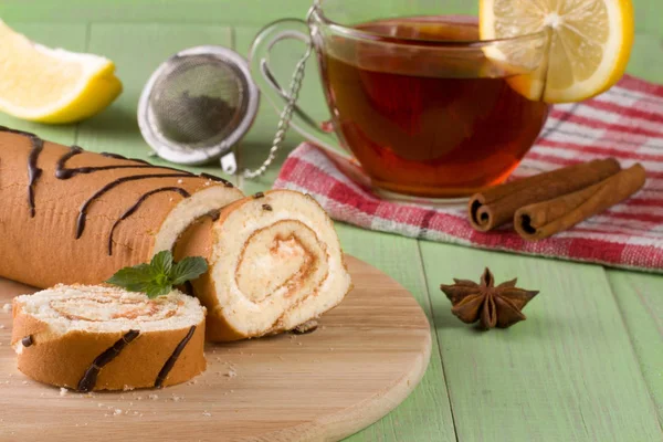 Biscotto rotolo svizzero con una tazza di tè su sfondo di legno verde — Foto Stock