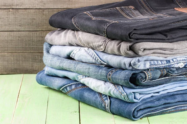 stack of jeans on  green wooden background