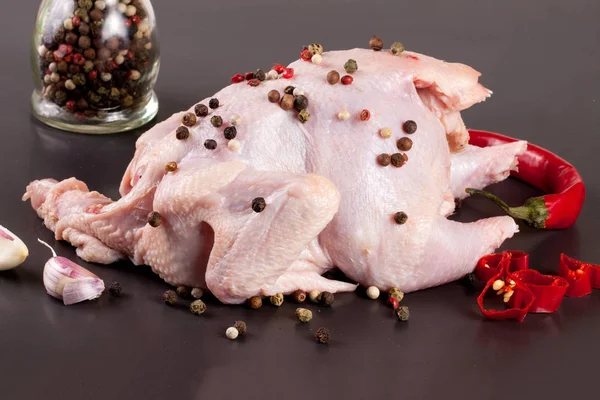 Rå kyckling kadaver med pepparkorn på en mörk bakgrund — Stockfoto