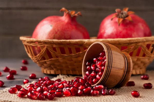 two pomegranate in a wicker basket and grains in the bowl on the old wooden board with sackcloth