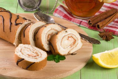 Bir fincan çay yeşil ahşap zemin üzerine ile bisküvi İsviçre rulo