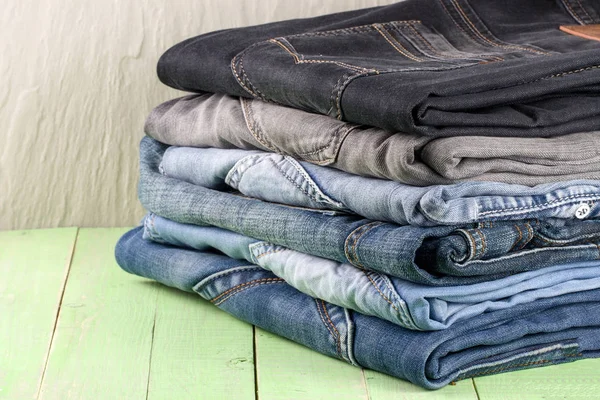 stack of jeans on green wooden background