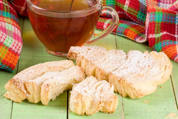 Zwei Blätterteigkekse mit einer Tasse Tee auf grünem Holzgrund — Stockfoto