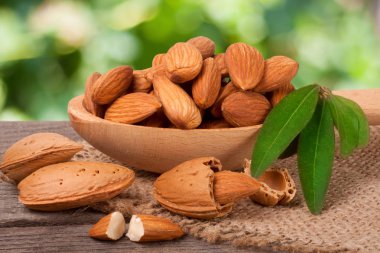 soyulmuş badem ile bir tahta kaşık masada yaprak yığını Bahçe arka plan bulanık